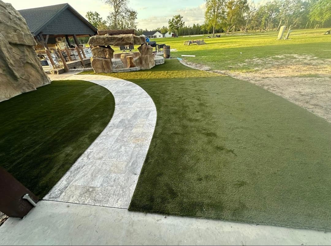 Artificial turf pathway leading to a landscaped area with natural stone features.