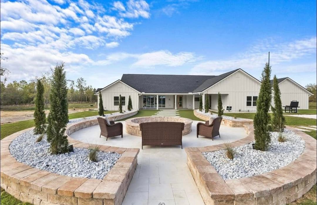 Modern outdoor seating area with stone landscaping and a spacious house in the background.