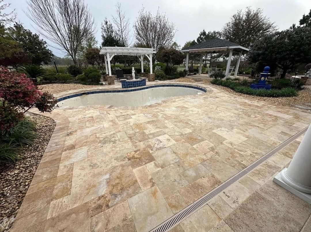 Elegant outdoor pool area with stone tiles, surrounded by lush greenery and amenities.