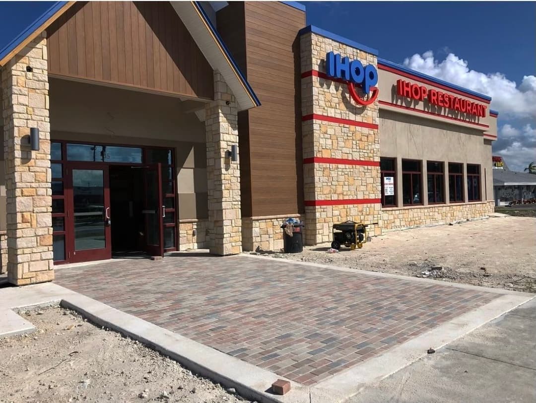 IHOP restaurant exterior with stone façade and paved entrance, clear blue sky above.