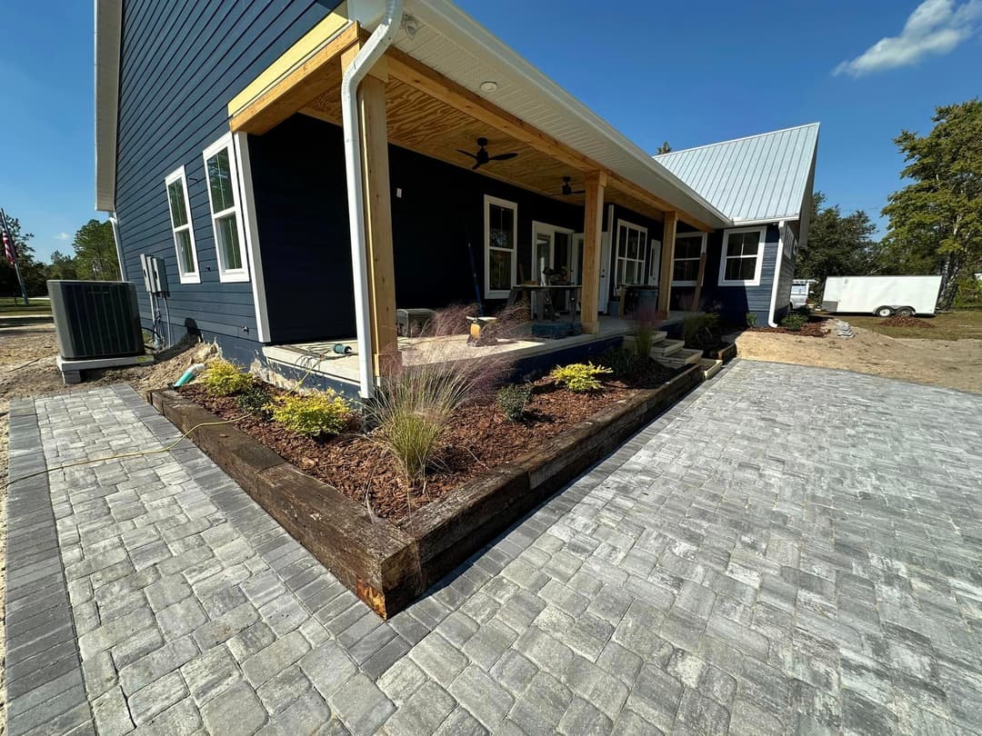 Modern home exterior with stone pathway, landscaped garden, and shaded porch.
