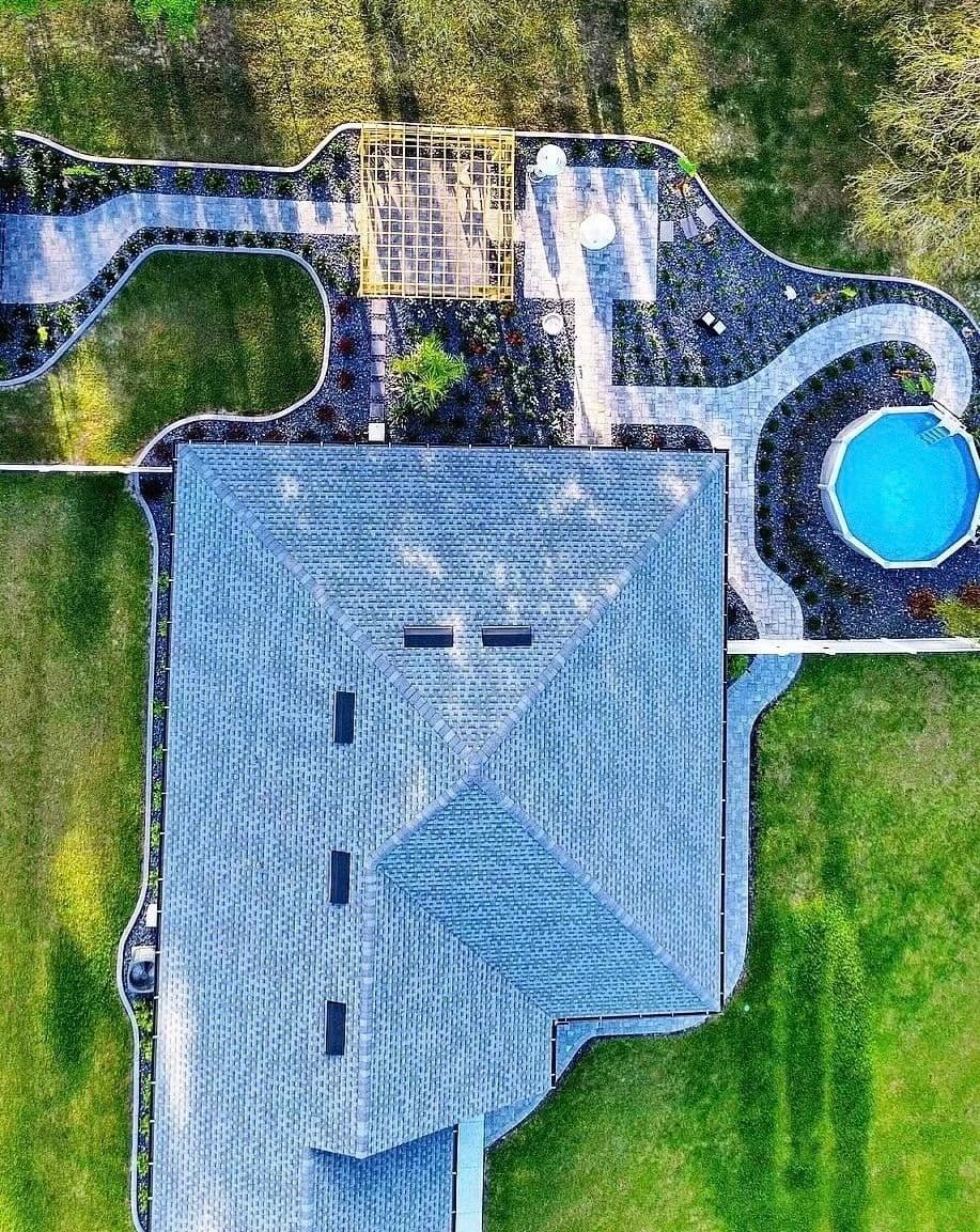 Aerial view of a landscaped backyard featuring a pool, patio, and garden pathways.