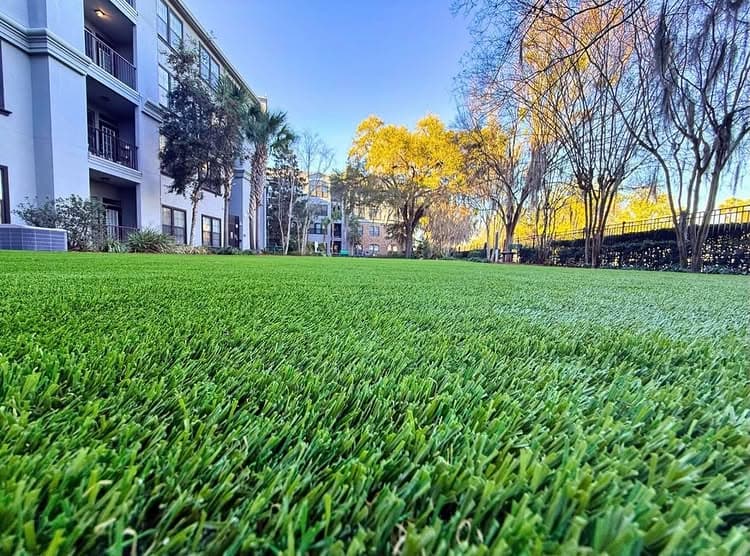 Vibrant green artificial grass in a serene apartment landscape under a clear blue sky.