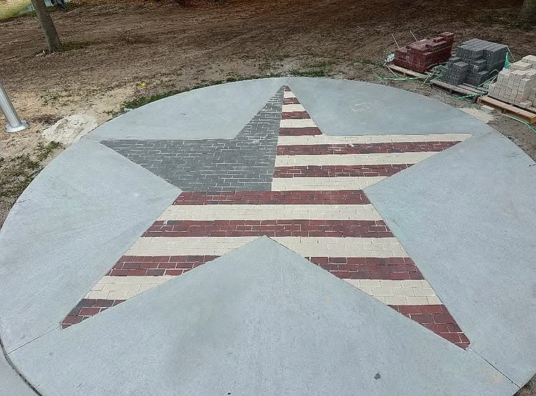 American flag-themed star created with brick pavers on a circular concrete base.